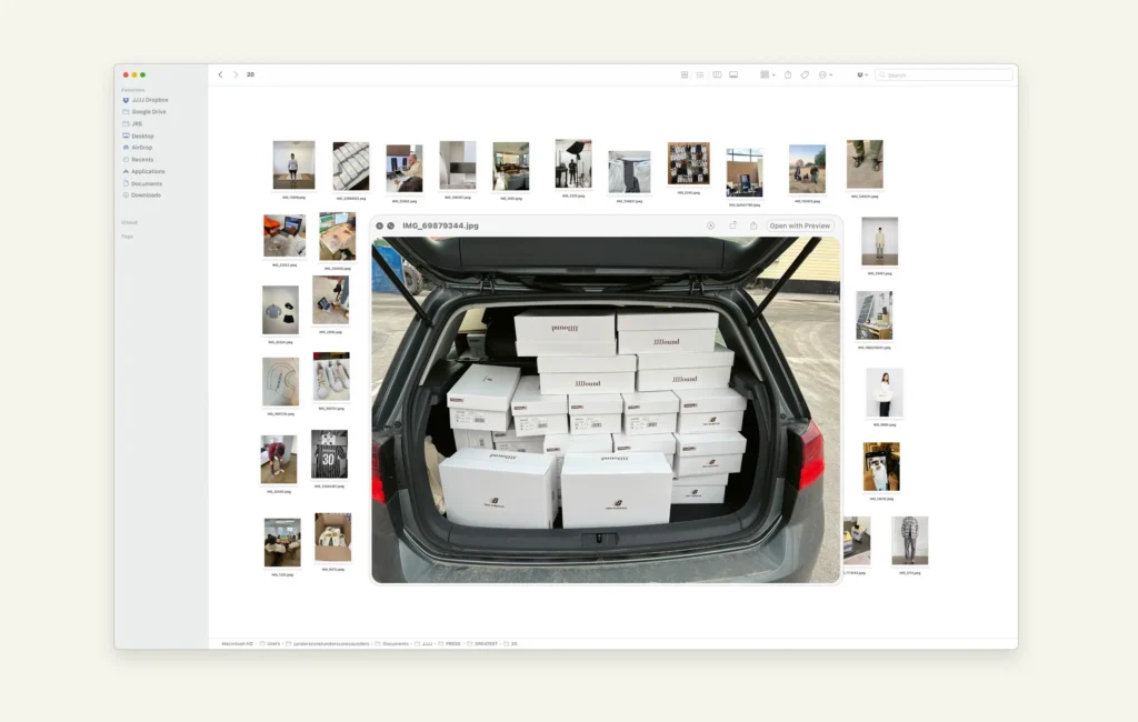 macOS Finder window displaying a curated image library, with the main preview showing the open trunk of a car filled with neatly stacked white shoe boxes labeled JJJJound and partner brands, surrounded by thumbnail images of apparel, objects, and studio scenes arranged in a clean, neutral-toned grid