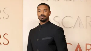 Michael B. Jordan in tailored black suit at Oscars event, minimalist formalwear with chain detail, embodying modern Hollywood elegance