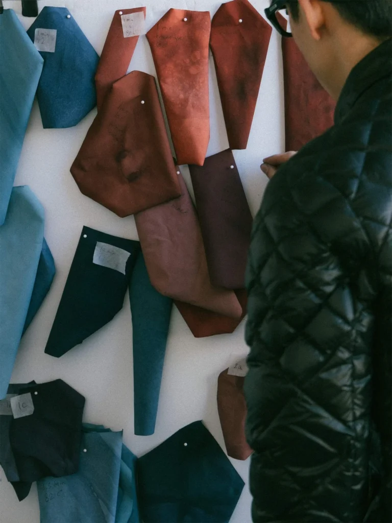 GORE-TEX fabric swatches in indigo and rust pinned to a wall during HAVEN’s experimental hand-dye development process