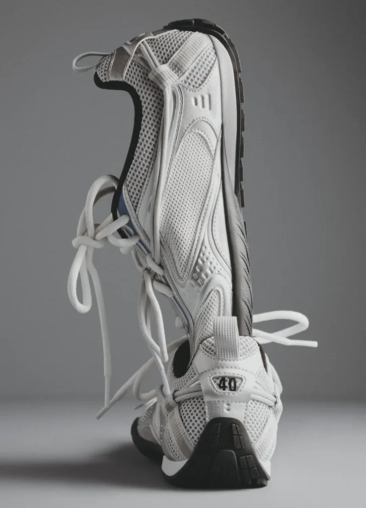 Balenciaga Radar Shoe in monochrome white shown in a sculptural stacked composition, highlighting its breathable mesh upper, streamlined low-profile silhouette, and wraparound lacing system; visible exposed shoe size “40” at the heel and subtle debossed detailing emphasize the brand’s signature coded design language and lightweight construction