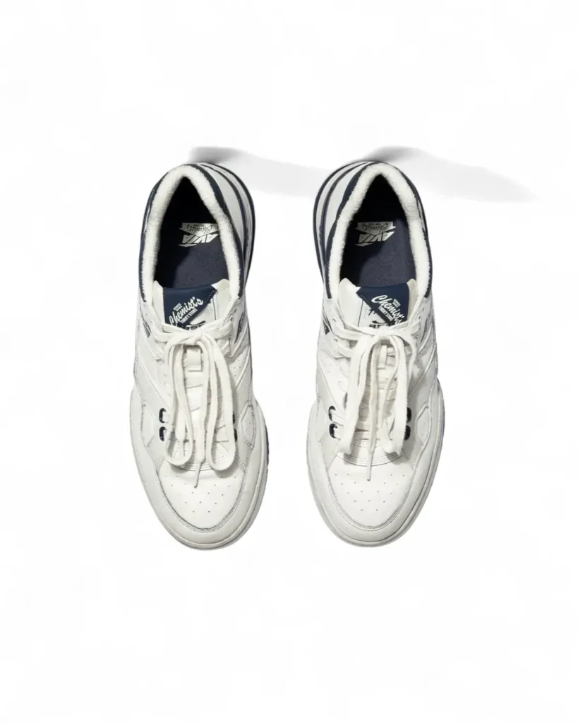 Top-down view of the Chemist Creations AVIA 855 sneakers showing cream leather uppers, oversized laces, perforated toe boxes, and Chemist’s® Thrift Store branded tongue labels