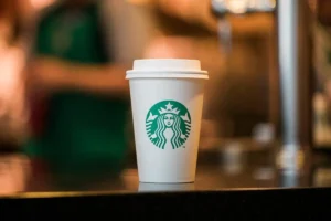 Starbucks takeaway coffee cup with the green siren logo placed on a café counter inside a Starbucks store