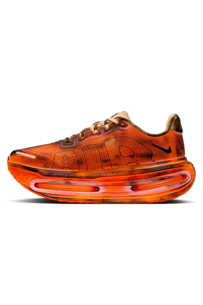 Side profile of the Melitta Baumeister x Nike Vomero Premium in Total Orange, featuring a distressed mesh upper with scorched detailing, black Swoosh, and exaggerated sculptural Air unit midsole
