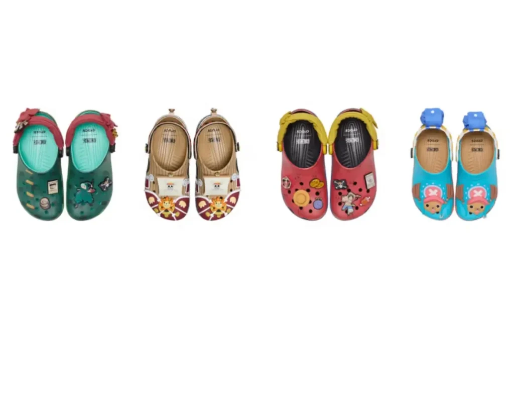 Four pairs from the ONE PIECE x Crocs Classic Clog Collection arranged side by side, including a green Roronoa Zoro themed clog, a tan Thousand Sunny ship design, a red Monkey D. Luffy pair with pirate Jibbitz charms, and a blue Tony Tony Chopper character clog