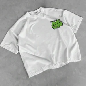 White oversized T-shirt laid flat on a neutral grey surface, featuring a small chest graphic with bold green graffiti-style lettering reading “Socially Awkward,” accented with black outlines for contrast