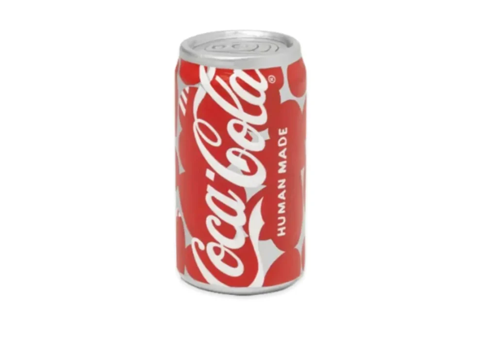 Red-and-white Coca-Cola can featuring an all-over heart motif pattern with co-branded “HUMAN MADE” text, reimagining the classic soda design with a play, graphic twist