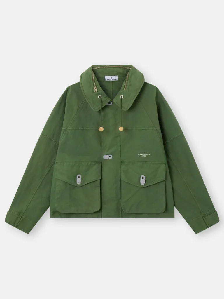 Green Stone Island Marina Nyco Panama-TC coach jacket laid flat against a neutral background, featuring a foldaway hood with drawstrings, front flap pockets with button closures, two-way zip fastening, adjustable cuffs, and subtle logo detailing on the chest