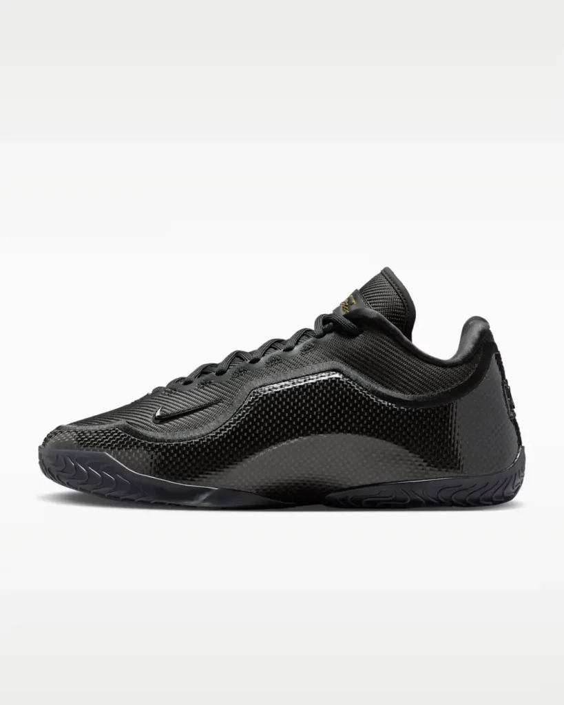 Lateral side view of Nike LeBron XXIII “Masked Menace” basketball shoe in black, highlighting textured woven upper, glossy carbon-fiber-style paneling, low-cut profile, and sculpted rubber outsole designed for multidirectional traction