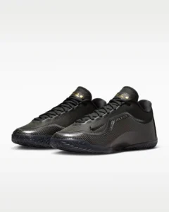 Pair of Nike LeBron XXIII “Masked Menace” basketball shoes in black, shown in angled front view with textured woven uppers, carbon-fiber-style side panels, gold signature tongue details, and low-profile performance build