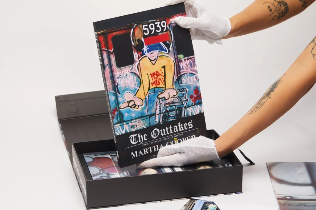 Hands wearing white gloves hold The Outtakes book by Martha Cooper from the Spray Nation limited edition box set featuring 1980s New York graffiti photography