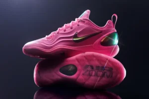 Hot pink Nike A’Two basketball shoe photographed in a studio setting, featuring a sculpted mesh upper, iridescent Swoosh logo, translucent outsole with visible traction pattern, and a glossy heel counter with reflective detailing