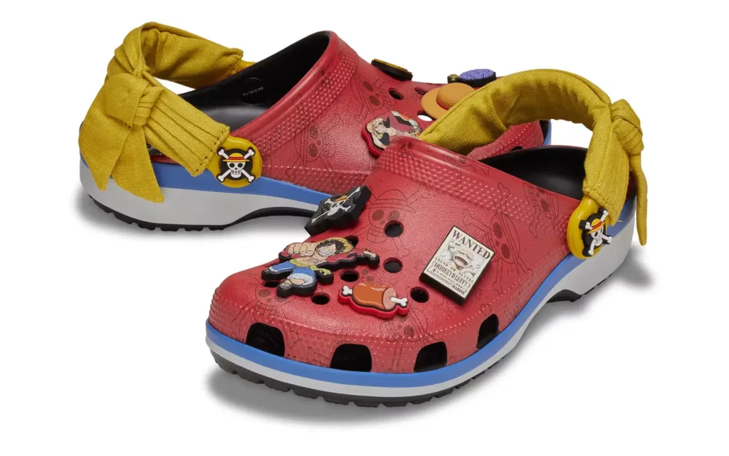 ONE PIECE x Crocs Classic Clog inspired by Monkey D. Luffy featuring red Croslite foam upper, Straw Hat pirate Jibbitz charms, and yellow sash-style heel straps