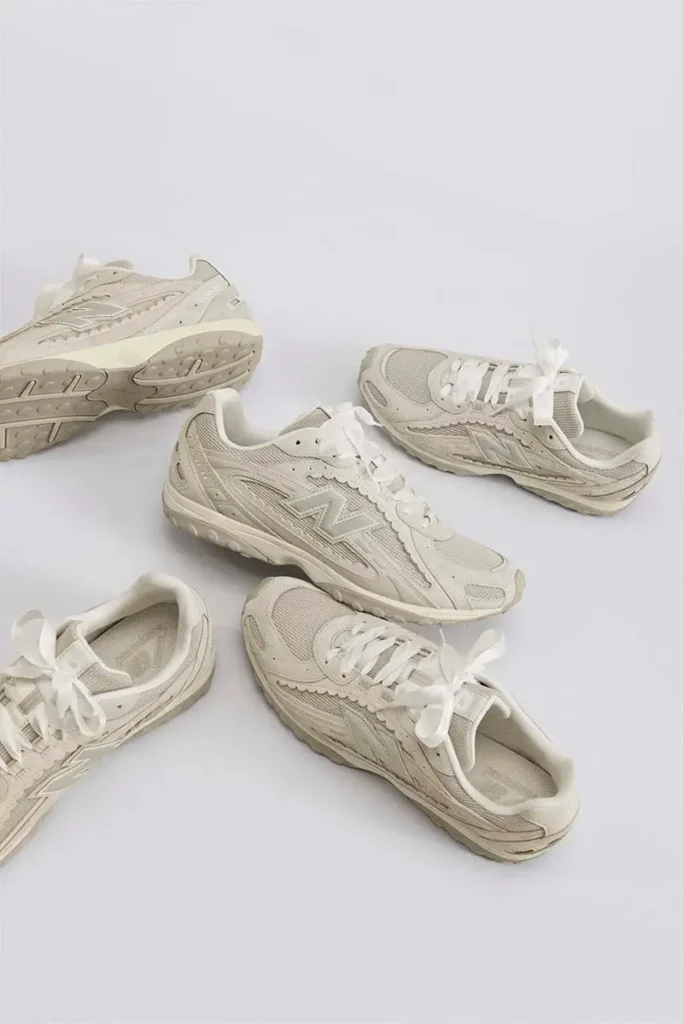 Group arrangement of New Balance 204L sneakers in a cream colorway displayed on a neutral background, highlighting the slim silhouette, mesh and suede construction, scalloped detailing, and ribbon-style laces