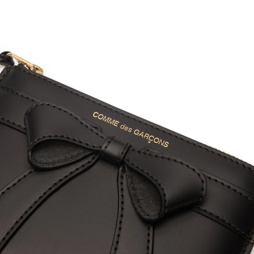 Back view of black Comme des Garçons Big Bow leather pouch with smooth leather panel, card slot detail, and gold zipper closure
