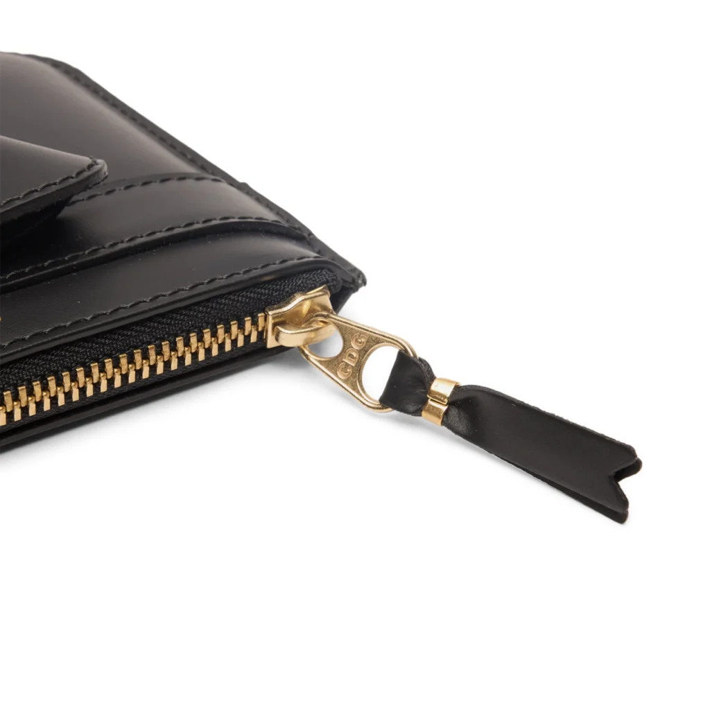 Close-up of gold zipper and leather pull tab on the black Comme des Garçons Big Bow leather pouch