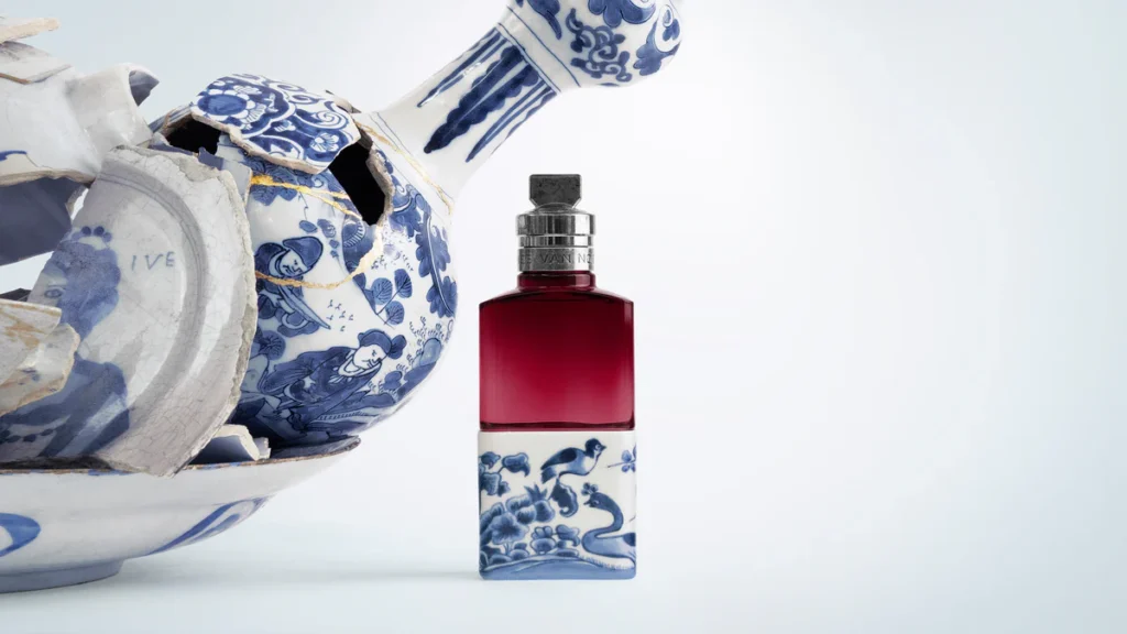 Dries Van Noten Soie Malaquais perfume bottle with red glass and blue porcelain base beside a broken ceramic sculpture with gold kintsugi repairs