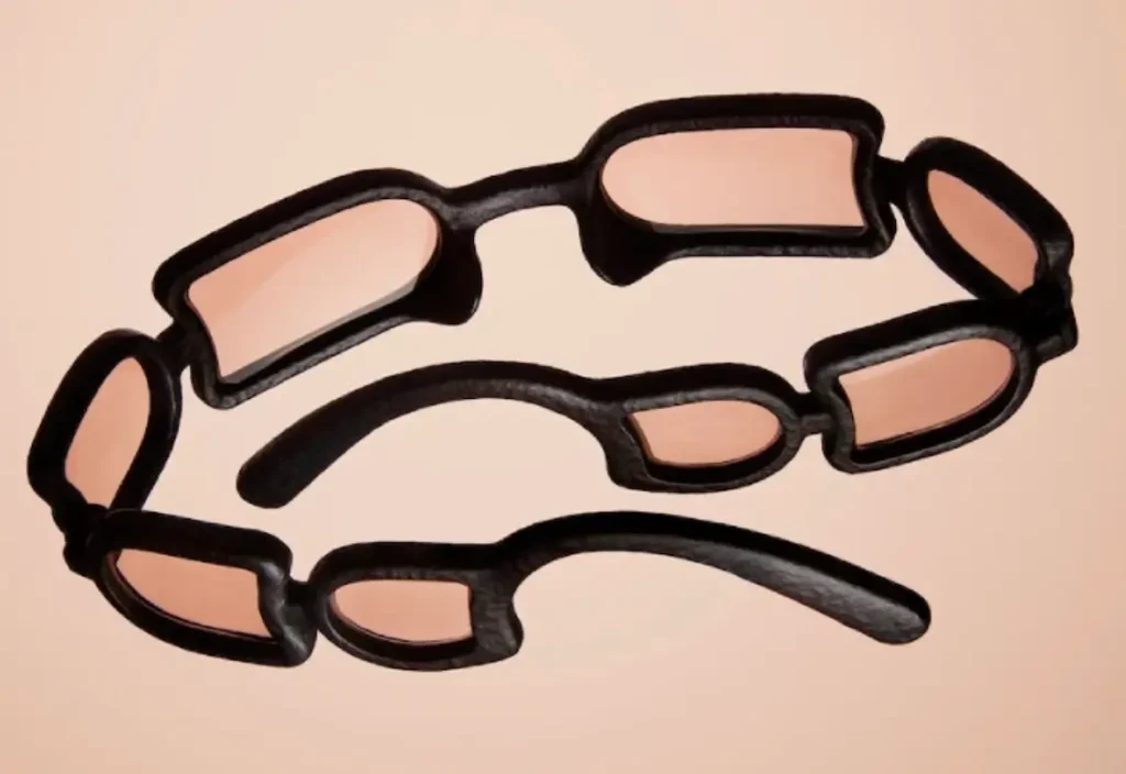 Issey Miyake Eyes UROKO sunglasses displayed from above, featuring eight concave lenses arranged in repeating segments within a sculptural black 3D-printed frame inspired by Shoji Kamoda’s ceramic scale patterns