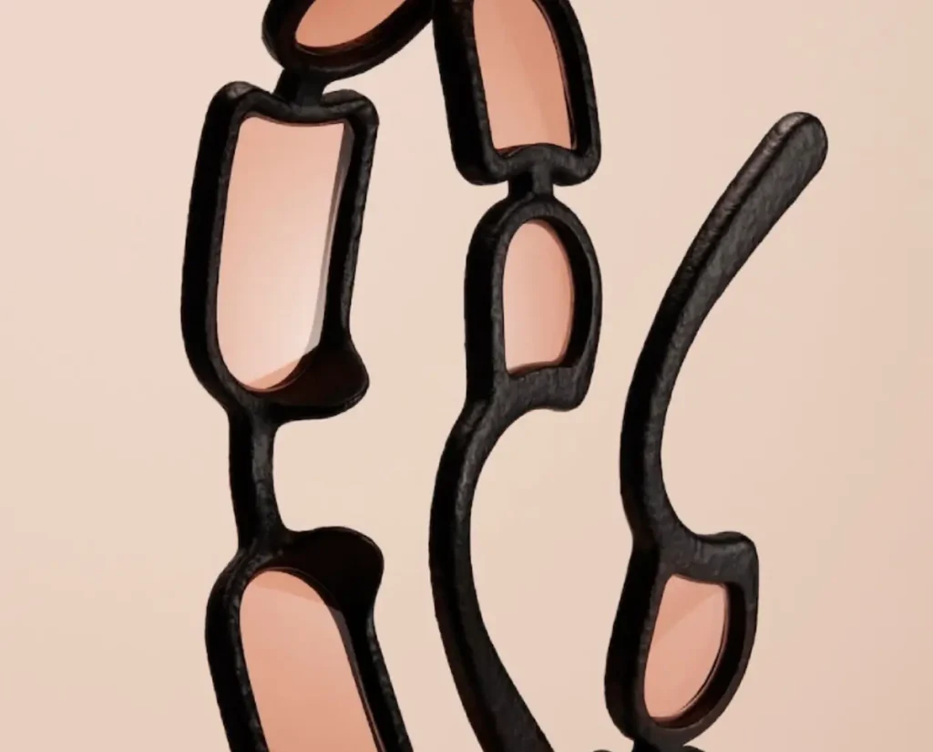 Close-up detail of Issey Miyake Eyes UROKO sunglasses showing elongated concave lenses set within a textured black 3D-printed frame, highlighting the segmented multi-lens structure inspired by Shoji Kamoda’s ceramic scale patterns