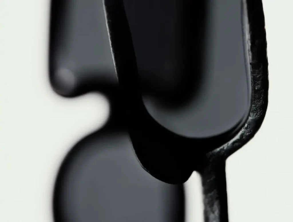 Macro detail of Issey Miyake Eyes UROKO sunglasses showing a concave dark-tinted lens set within a textured black 3D-printed frame, highlighting the sculptural multi-lens structure inspired by Shoji Kamoda’s ceramic scale motifs