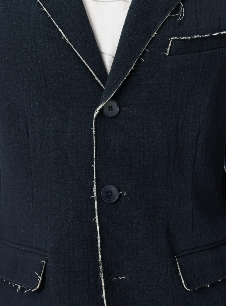 Close-up of the navy John Varvatos Knox Jacket showing raw edge stitching along the lapels, three-button front closure, textured double-faced cotton fabric, and chest welt pocket detailing