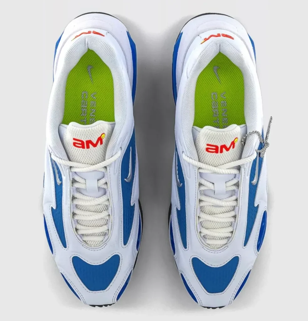 Top-down view of the Veneda Carter x Nike Air Max Muse sneakers in white and racer blue, featuring metallic Swooshes, rope laces, orange “AM” tongue branding, and volt green insoles with Nike logo
