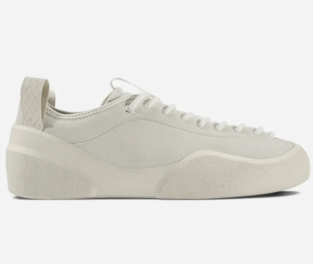 Side profile of the Village PM 1PM shoe in cream, showcasing a smooth suede upper, tonal lace system, and a sculpted off-white sole with a clean, flowing minimalist design