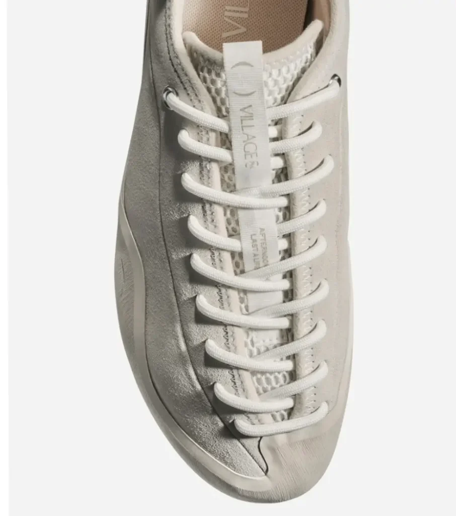 Top-down view of the Village PM 1PM shoe in cream, highlighting tonal laces, a breathable mesh tongue, suede upper panels, and a vertical VILLAGE PM branded pull tab at the center