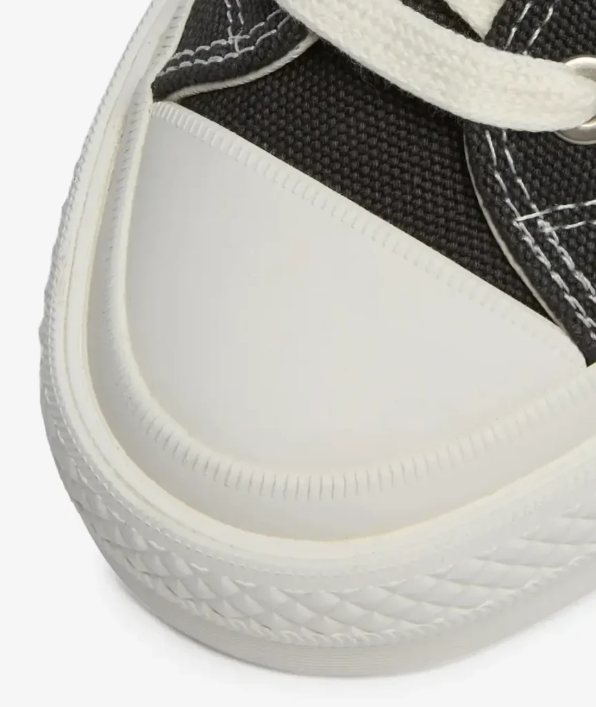 Close-up detail of Converse First String Chuck Taylor All Star Hi, highlighting off-white rubber toe cap, textured foxing with diamond pattern, and tightly woven Beluga canvas with contrast stitching