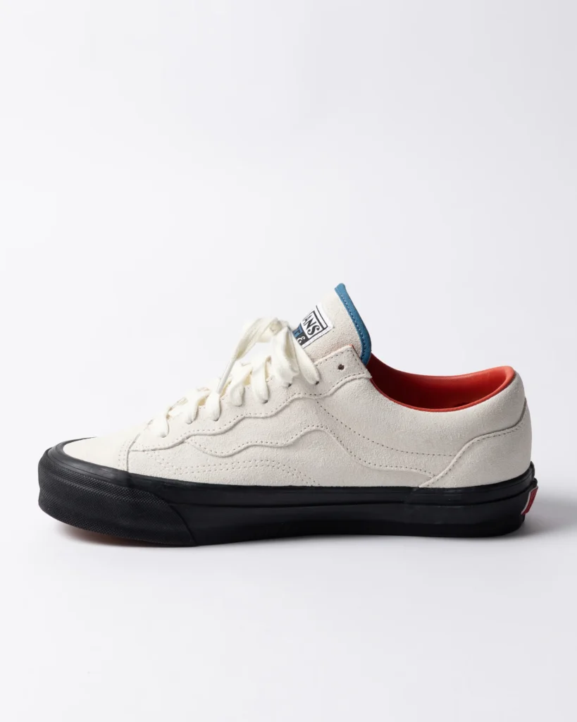 Side profile of Parra x Vans OTW Old Skool 36 “Marshmallow” sneaker in off-white suede, featuring tonal wavy paneling, white laces, blue tongue trim, orange inner lining, and a black vulcanized sole against a clean studio background