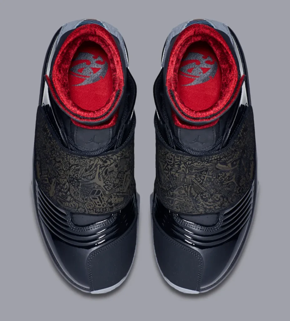 Overhead view of the Air Jordan 20 “Stealth” 2015 retro sneaker featuring engraved storytelling graphics across the midfoot shroud, black patent leather upper, plush red inner lining, and Jumpman branding on the insole