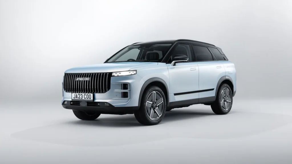 Three-quarter front view of the Jaecoo 7 SUV in a light blue finish, featuring a bold vertical-slat grille, slim LED headlights, black roof contrast, and geometric alloy wheels against a clean studio background