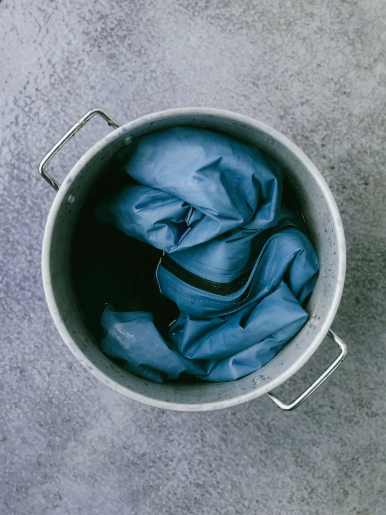 Indigo-dyed GORE-TEX garment inside a metal dye pot during the HAVEN hand-dye experimentation process