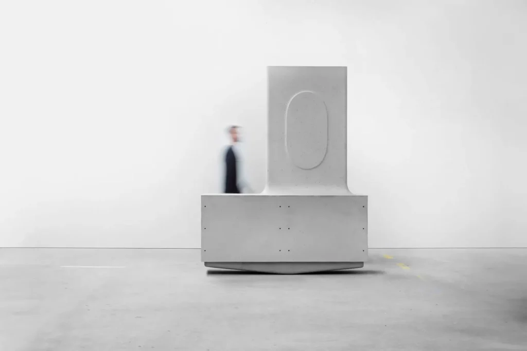 Large sculptural concrete module from MIT’s Heirloom House project with a blurred person walking past, illustrating the scale of the modular architectural component