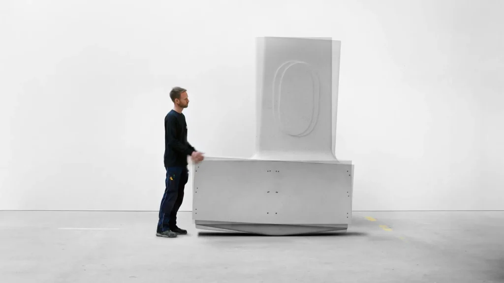 Person demonstrating a modular concrete component from MIT’s Heirloom House project, a structural element designed by Matter Design and Cemex for a 1,000-year adaptable housing system