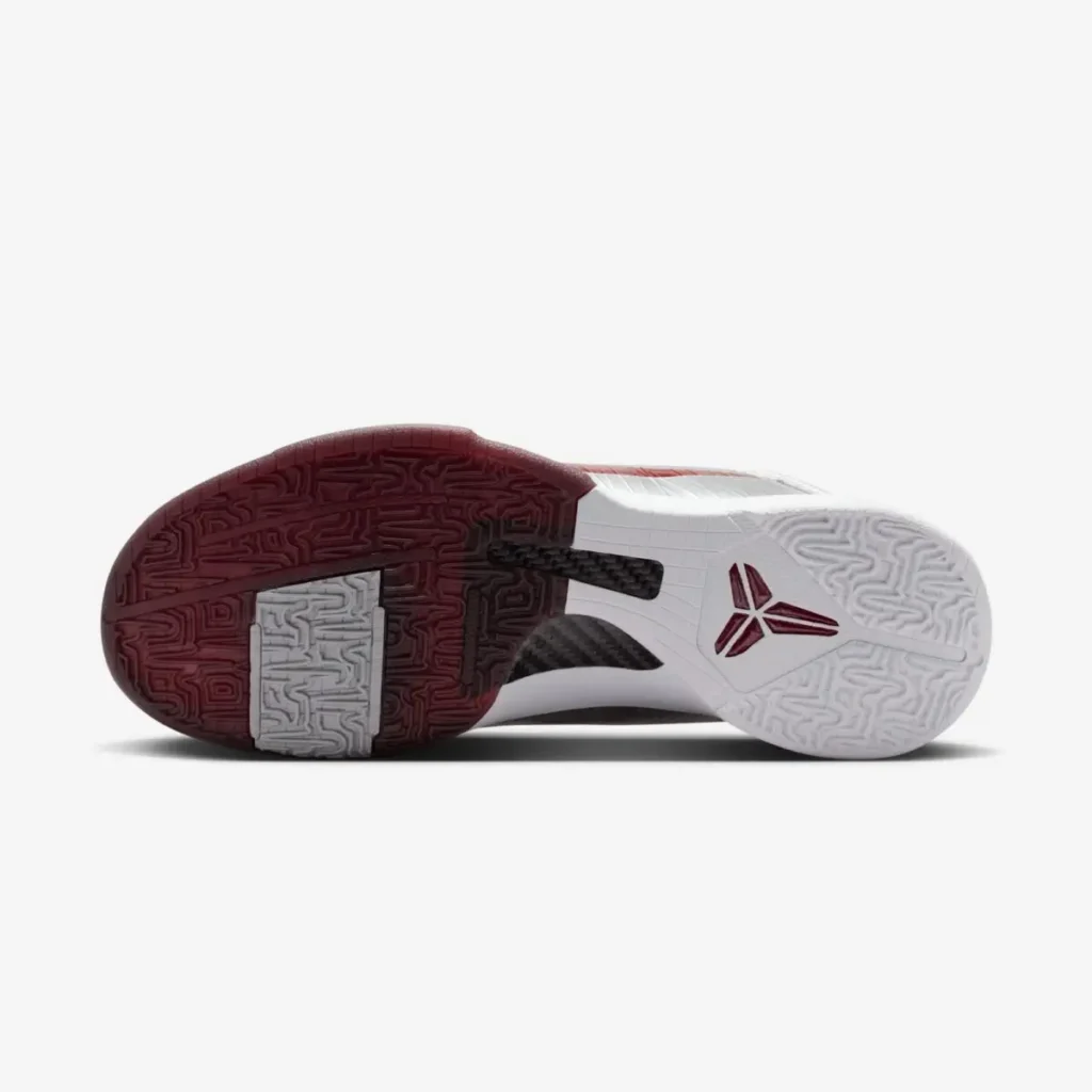 Underside of the Nike Kobe 5 Protro “Lower Merion Aces” basketball shoe highlighting carbon fiber shank, Kobe logo, and dual-tone traction rubber