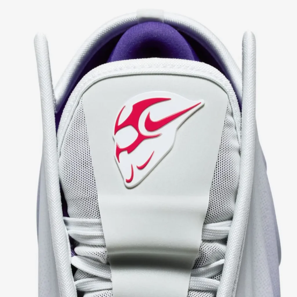 Close-up of the Nike G.T. Future tongue featuring the Swooshman logo in bold red, set on a smooth molded panel with white laces and a purple inner lining