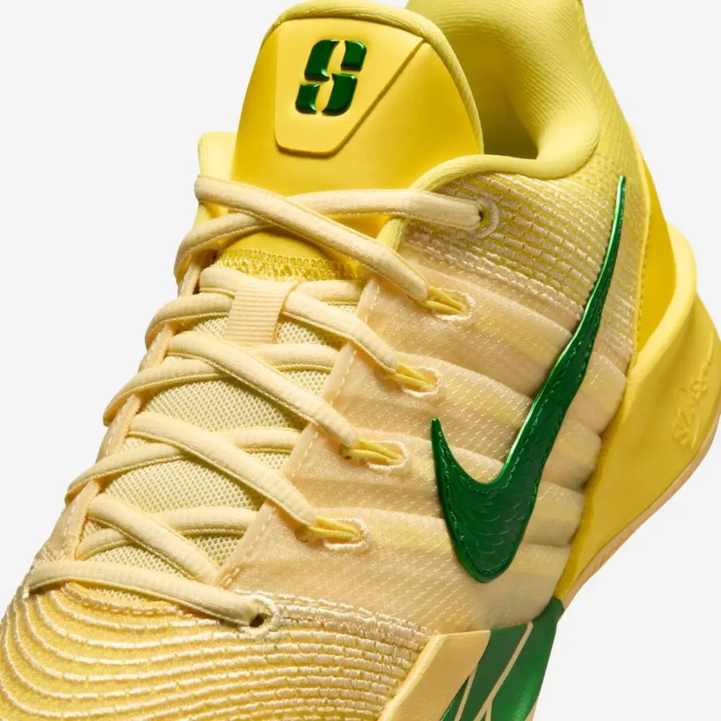 Close-up front view of the Nike Sabrina 3 “Oregon Ducks” basketball shoe showing a yellow mesh upper, cream laces, glossy green Nike Swoosh, and Sabrina Ionescu “S” logo on the tongue