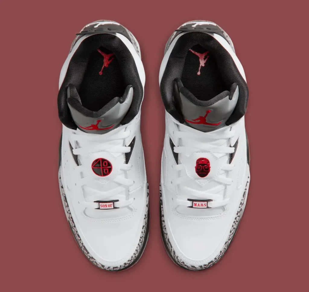 Top-down view of Jordan Son of Mars “White Cement” sneakers showing white leather uppers, red Jumpman logos on grey tongues, Mars Blackmon and 40 Acres lace locks, and elephant print mudguards