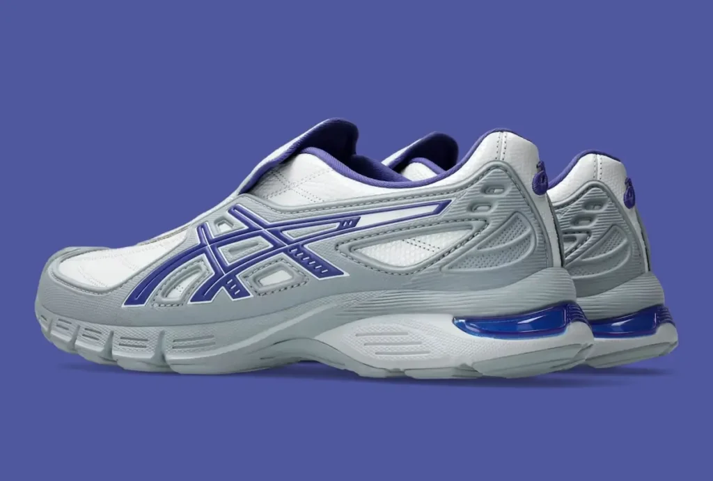 Rear-side view of the OTTO 958 x ASICS Gel-SD Arzachotto in white, grey, and blue, showcasing the laceless slip-on construction, quilted upper, layered grey heel structure, bold blue ASICS Tiger Stripes, and a sculpted midsole with visible blue cushioning detail at the heel