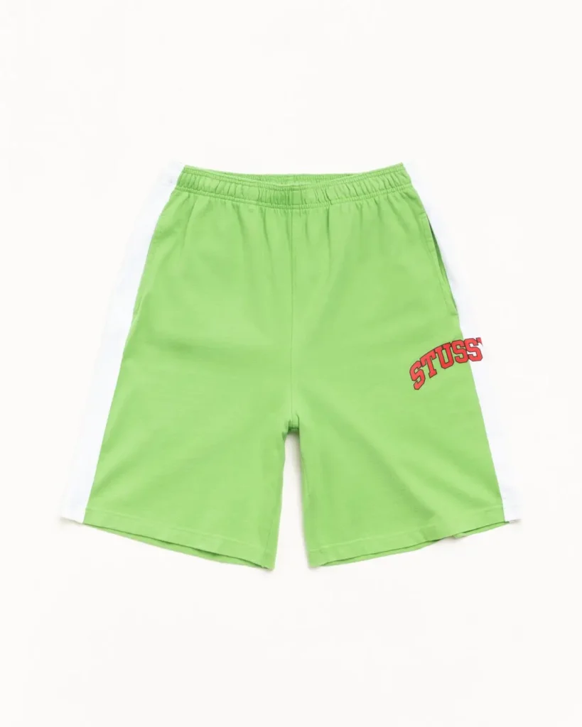 Bright green athletic shorts with elastic waistband, white side panels, and red Stüssy logo printed on the lower right leg