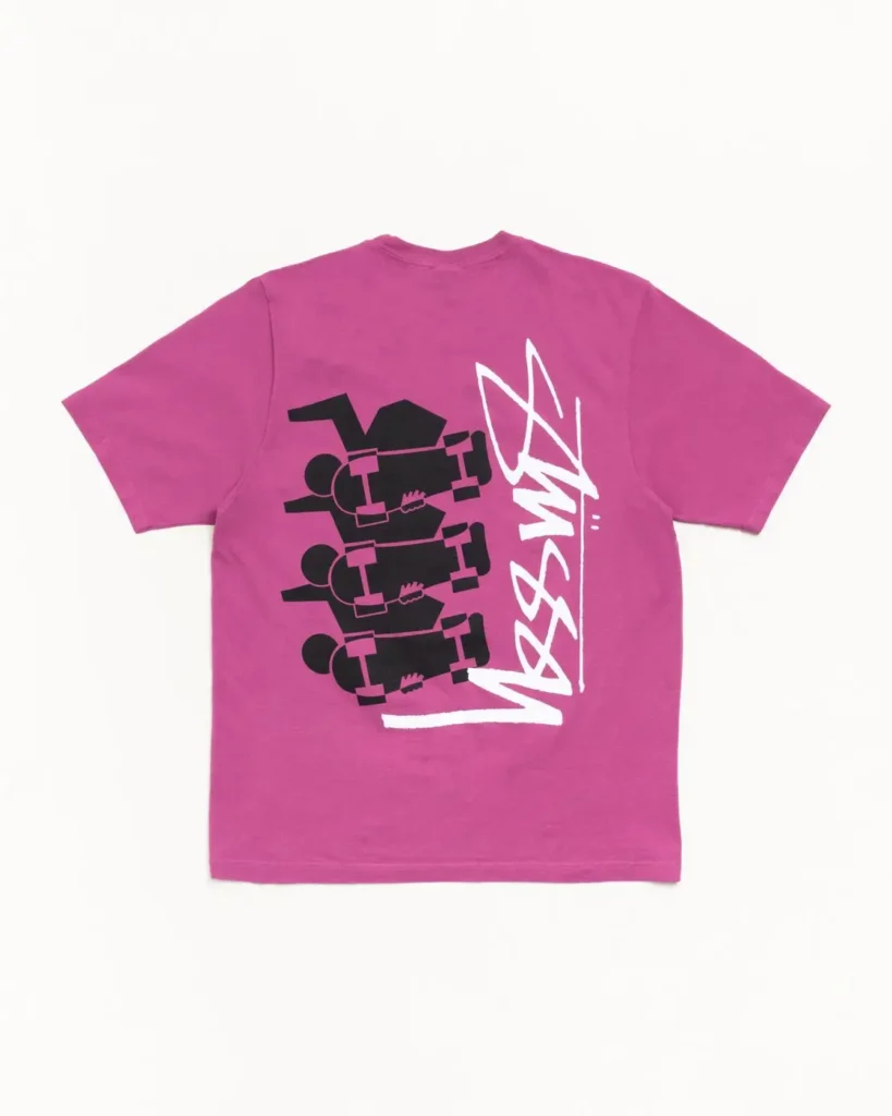 Pink short-sleeve graphic T-shirt featuring black skateboarder illustrations and a large white Stüssy signature logo printed across the back