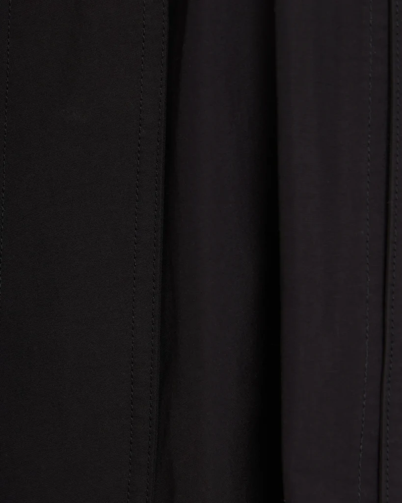 Extreme close-up of black The North Face jacket fabric showing smooth matte texture and clean vertical seam stitching