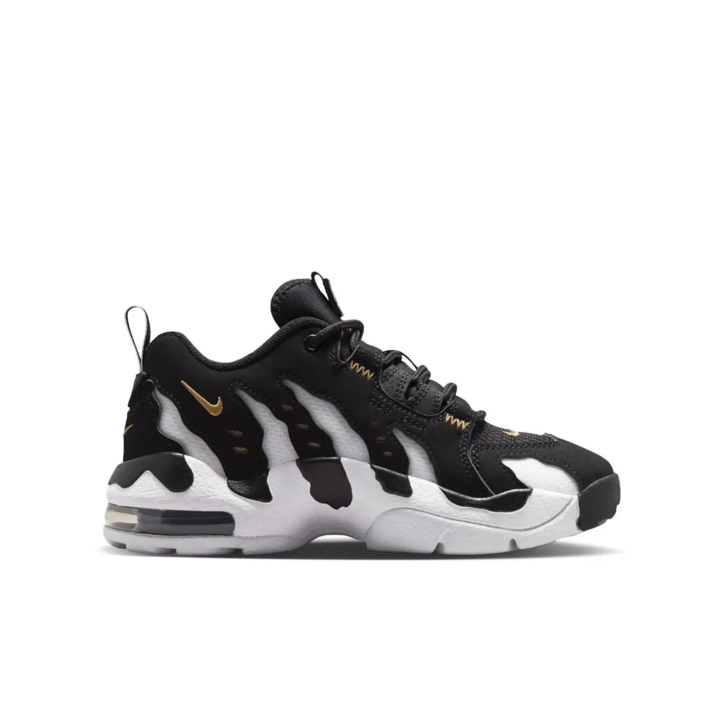 Side profile of a Nike shoe in a black, white, and gold colorway, featuring a layered upper with flowing, wave-like black overlays atop a white mesh base. A small metallic gold Swoosh appears near the heel, while gold stitching accents the lace area. The shoe sits on a chunky white midsole with sculpted contours and a visible Air unit in the heel, paired with black rubber detailing at the outsole and toe