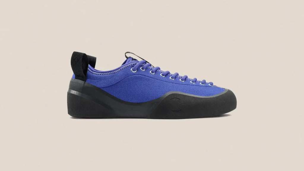 Side profile of VILLAGE PM 1PM sneaker in natural purple canvas with sculpted black rubber sole and toe wrap, tonal laces with metal eyelets, and rear pull tab, set against a clean neutral backdrop