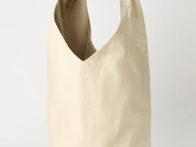 Our Legacy DRIP BAG in deep ecru leather shown in a relaxed upright stance, featuring a soft cylindrical body, curved open top with a padded integrated handle, fine natural grain texture, central stitched seam, and a clean, unembellished finish against a neutral studio background