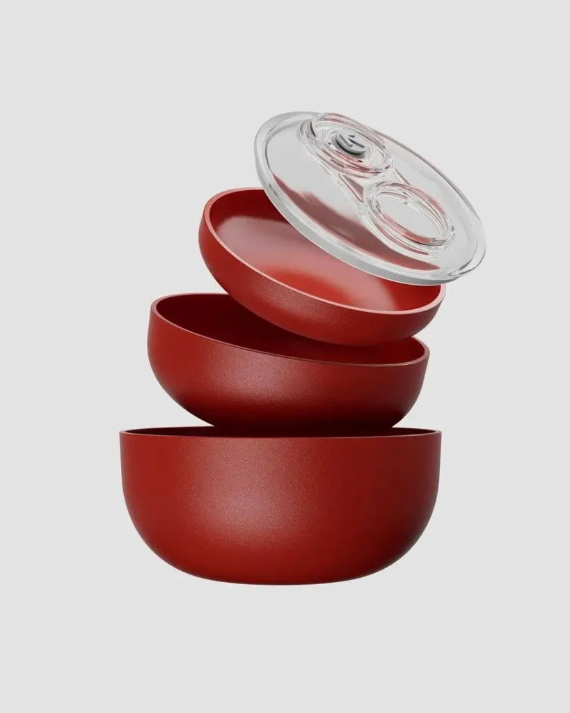 Product shot of the red B!POD DRO!D vacuum storage containers stacked and nested against a clean background. The premium matte red bowls showcase their rounded, stackable design with one transparent vacuum lid lifted, revealing the precision sealing mechanism. Highlighting the elegant Italian craftsmanship and modular food preservation system, 2026