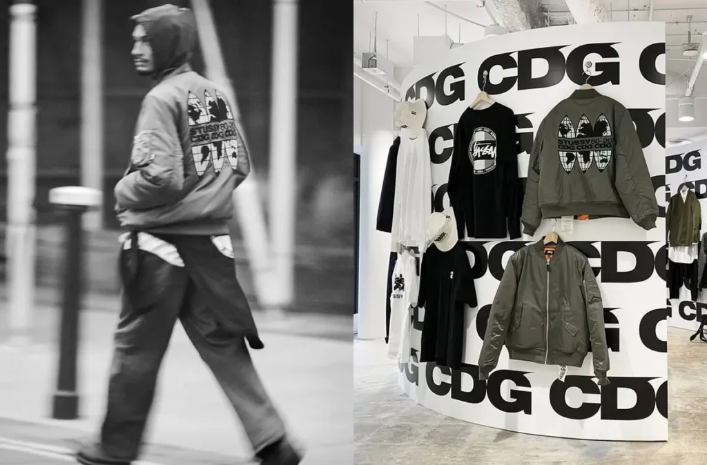 Black-and-white street shot of a model in a CDG bomber jacket alongside a retail display featuring CDG and Stüssy collaboration pieces against a bold logo-covered backdrop