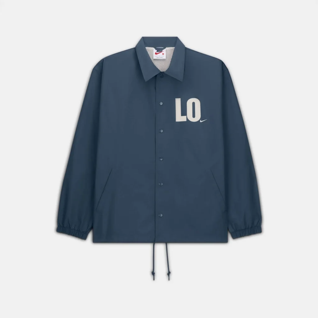 Minimal navy coach jacket with a clean, structured silhouette, featuring snap-button closure, elasticated cuffs, and adjustable drawstring hem. A subtle white “LO” graphic with a small Swoosh sits on the chest, while the interior mesh lining peeks through at the collar, balancing understated branding with functional design