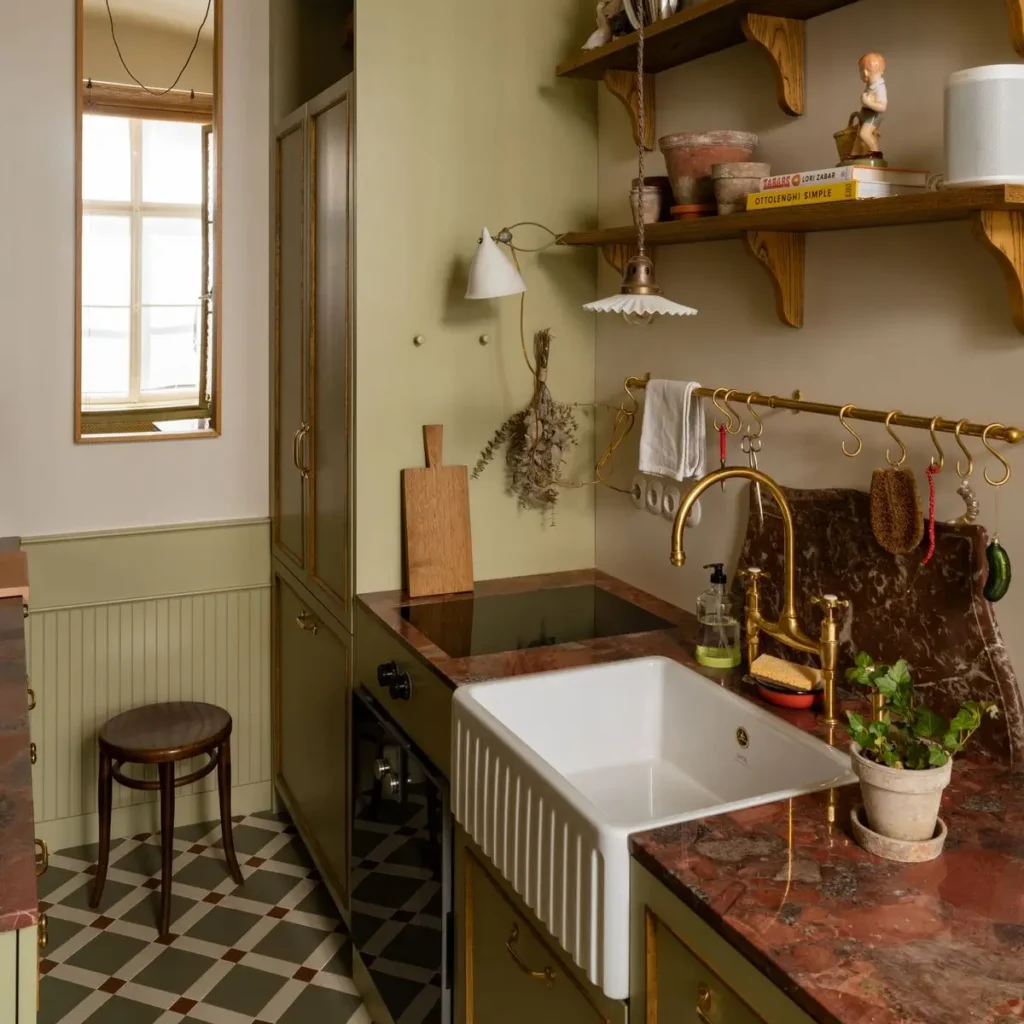Vintage-inspired kitchen corner with marble countertops, brass fixtures, farmhouse sink, open wooden shelving, and patterned tile flooring in soft natural light