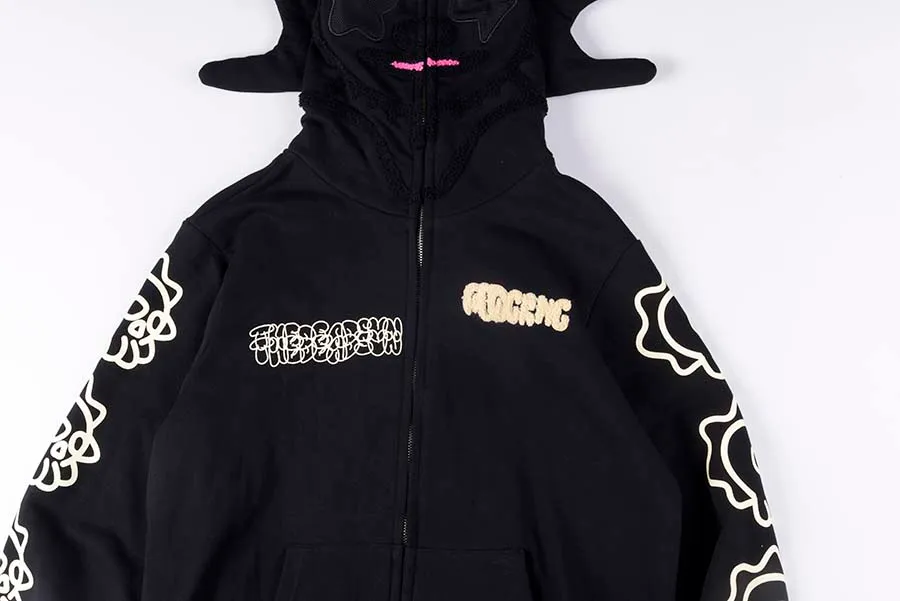 Black Glo Gang Glo Man full zip hoodie featuring a sculpted character hood with spiked extensions and subtle facial detailing, front zipper closure, chenille “GLOGANG” chest logo, stylized script graphic, and bold white sleeve prints on a neutral background